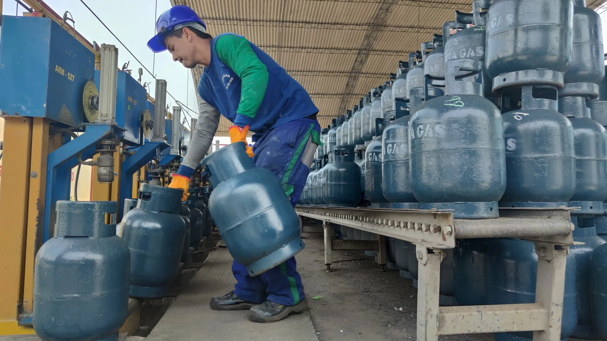 Operario de Anta Gas con casco y guantes llevando un balón a la línea de llenado